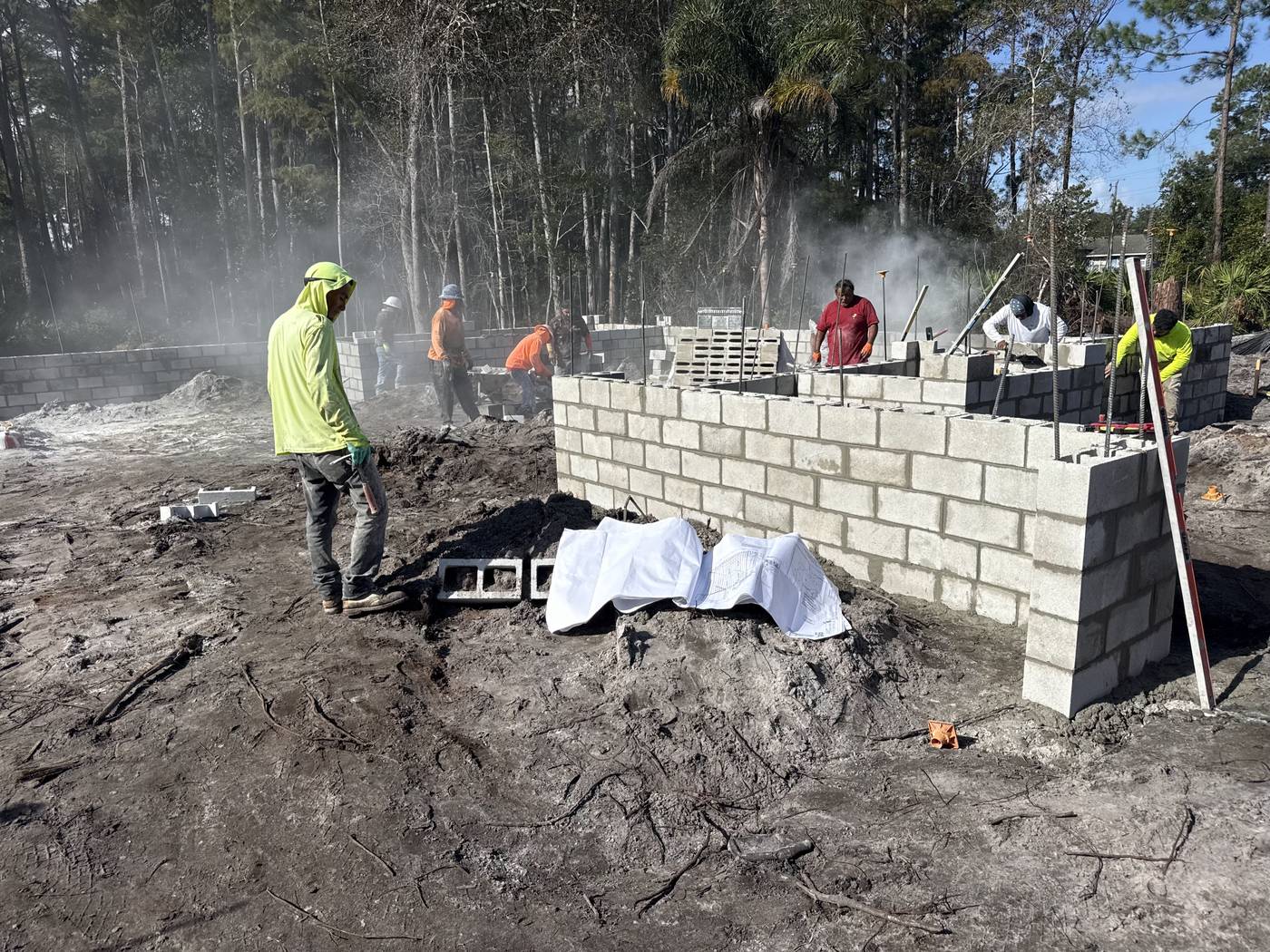 Crew laying concrete block for the stem wall at Captain Drive, with the corner of the wall in the foreground