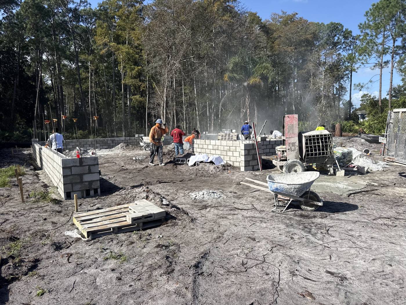 Wide view of the Captain Drive lot with the block stem wall outlining the house and the crew at work